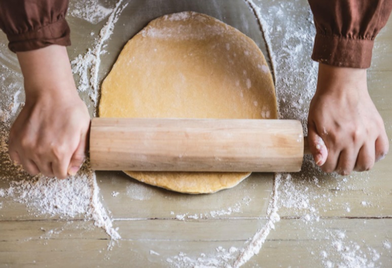 photo of hands on a rolling pin with pie dough